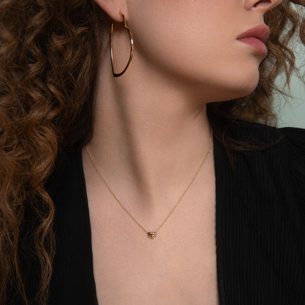 Model wearing a heart necklace and oversized heart hoop earrings
