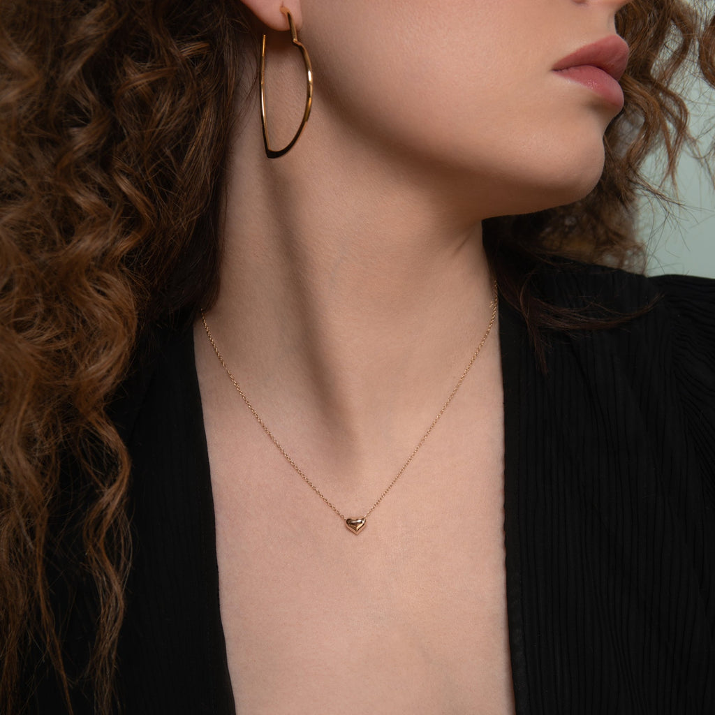 Model wearing a Delicate gold heart necklace and oversized gold heart hoop earrings
