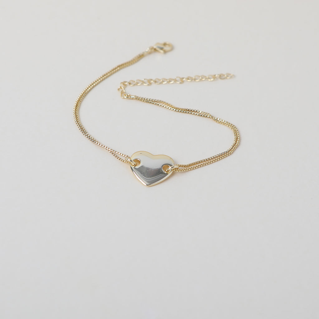 Gold twin chain bracelet featuring a smooth gold heart