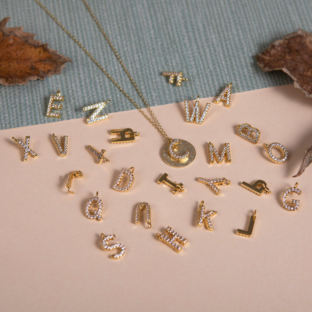 Alphabet Charm letter C on a distressed coin necklace with alphabet charms scattered around it